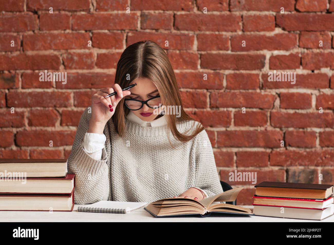 Giovane ragazza leggere attentamente materiale in biblioteca Foto Stock