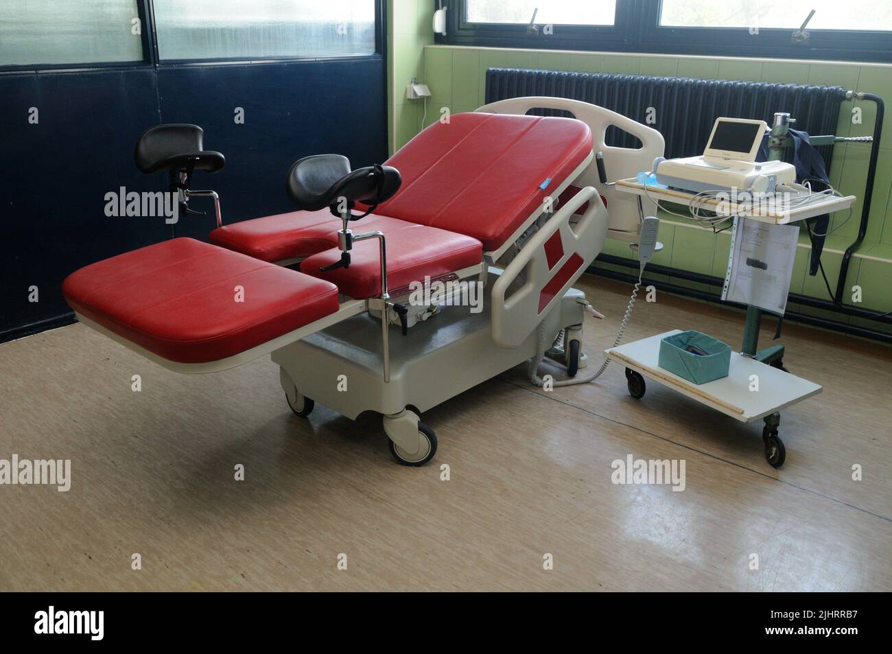 Una sedia-letto ginecologica rossa nella stanza dell'ospedale Foto Stock