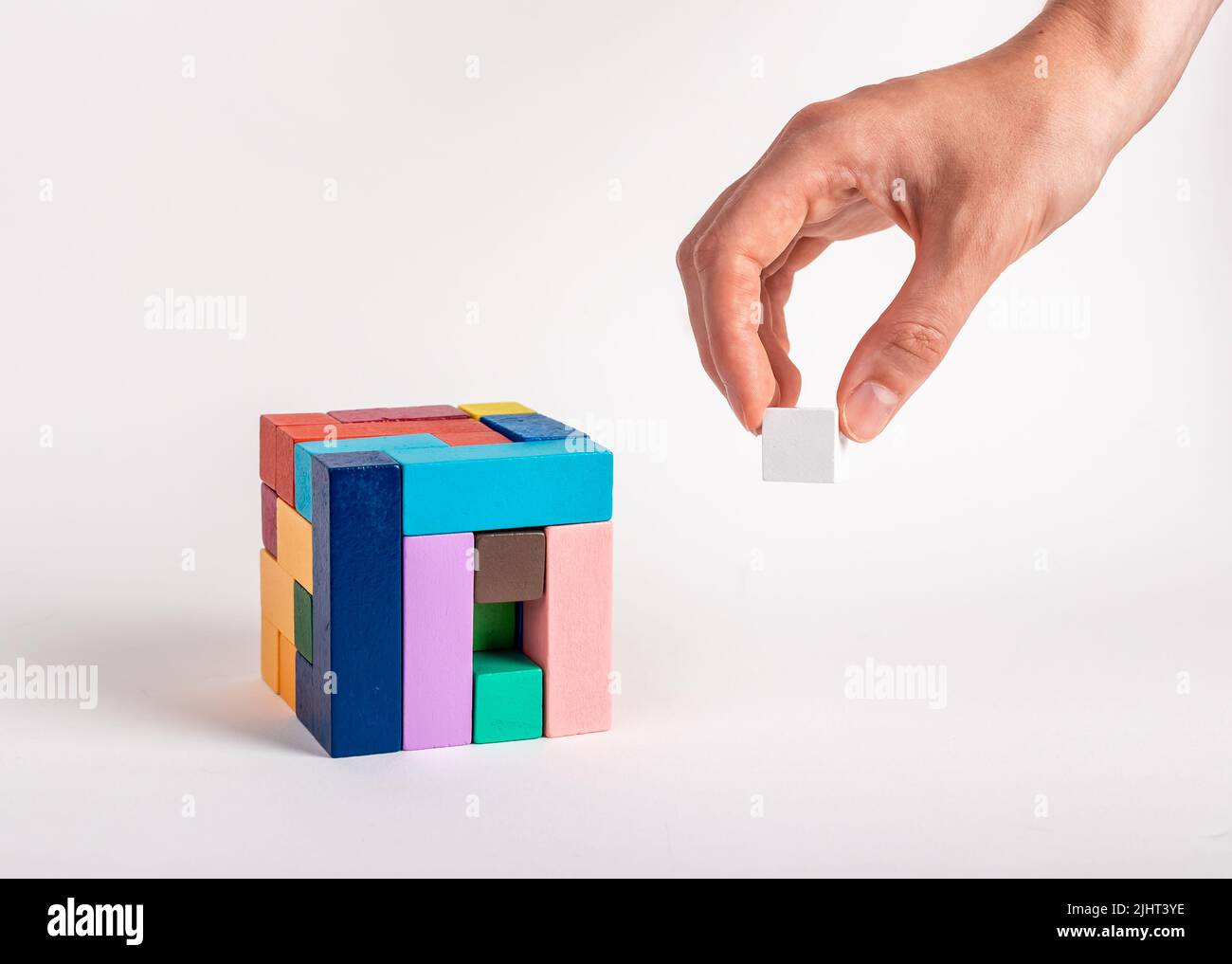 Donna arrangiando cubo puzzle mettendo elemento mancante. Costruzione, formazione o concetto riuscito di completamento di lavoro. Giocattolo logico in legno per bambini. Processo decisionale. Foto di alta qualità Foto Stock