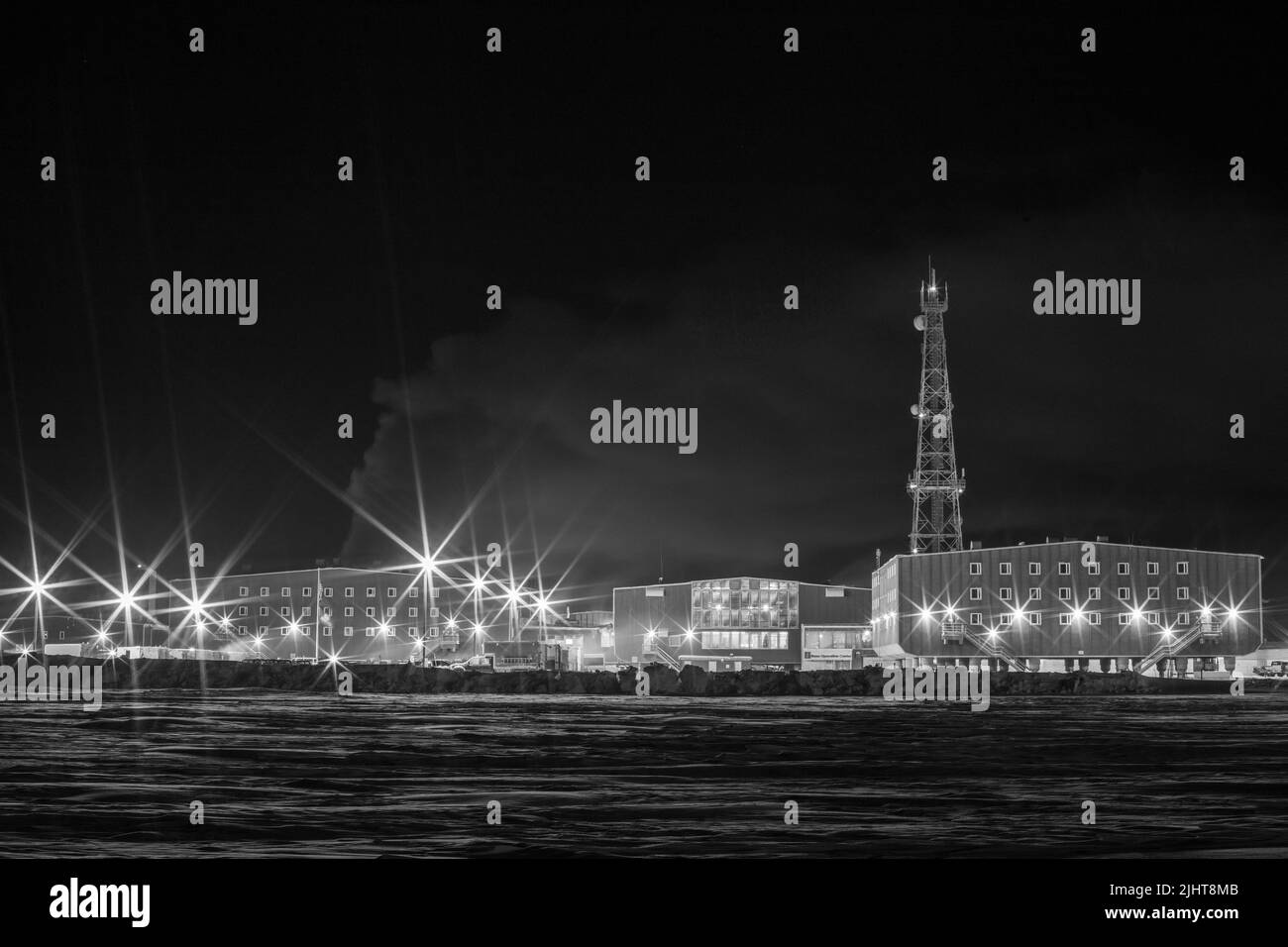 Una scala di grigi di edifici luminosi con un fiume in primo piano Foto Stock