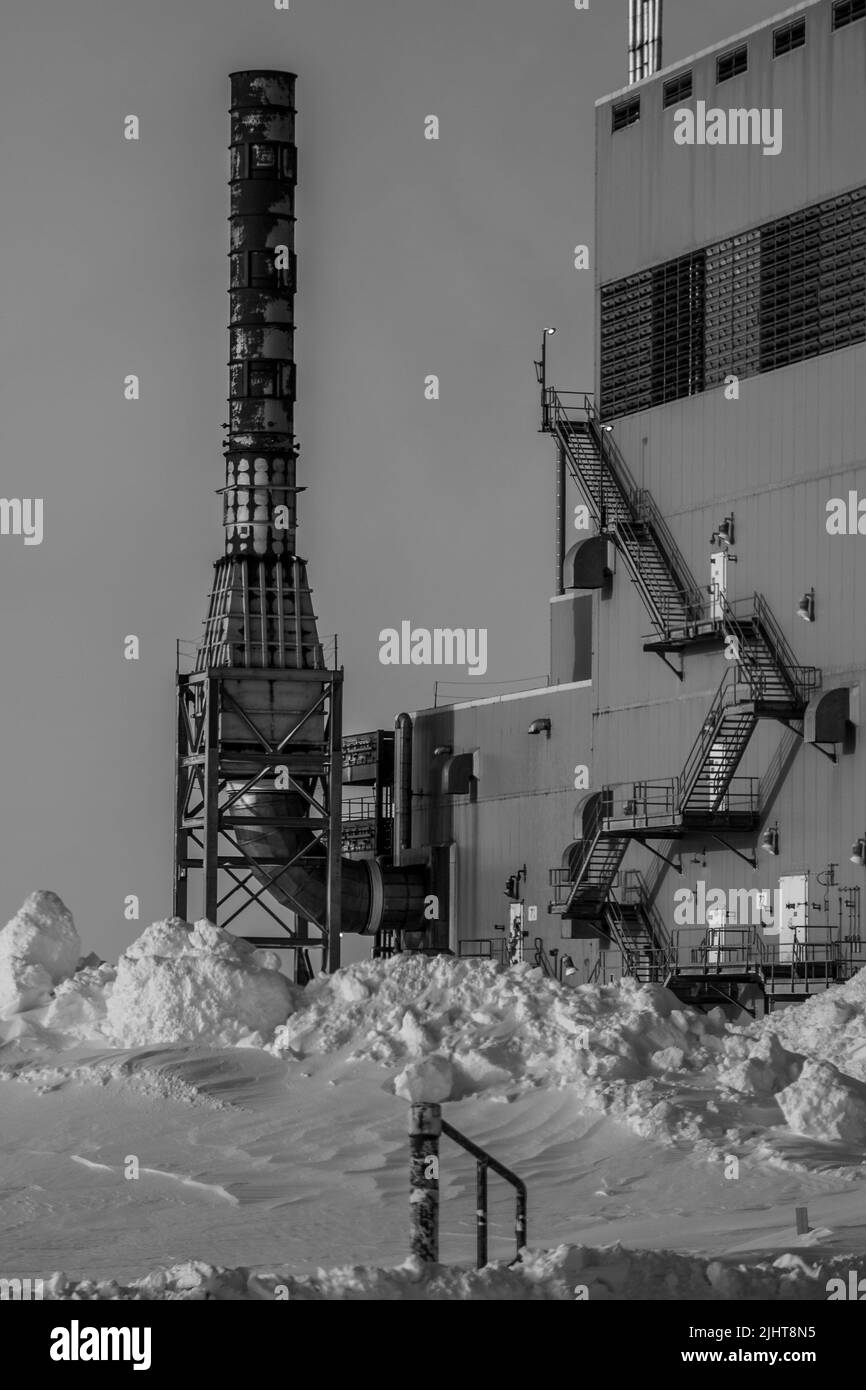 Un colpo verticale di una fabbrica in inverno con un cielo chiaro sfondo Foto Stock