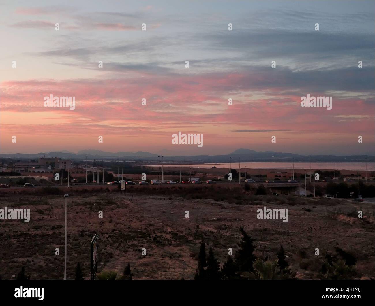 Un'immagine panoramica di un campo secco con le Las Salinas de Torrevieja ad Alicante, Spagna, al tramonto Foto Stock