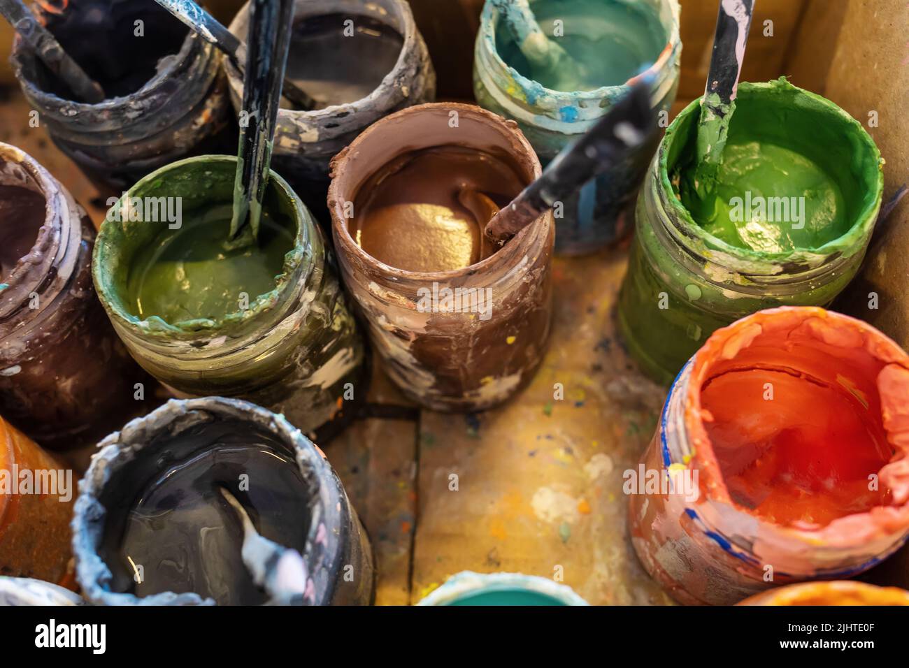 Vasetti aperti con vernici multicolore in scatola di cartone. Aprire le vernici in un laboratorio d'arte. Attività creative Foto Stock