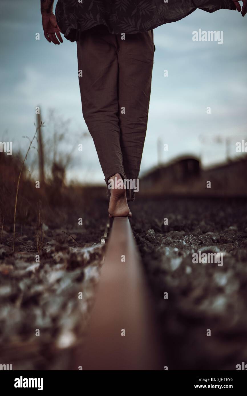 Uomo casual a piedi nudi sulla ferrovia. Dettaglio su gambe e piedi, libertà e concetto di sogno Foto Stock
