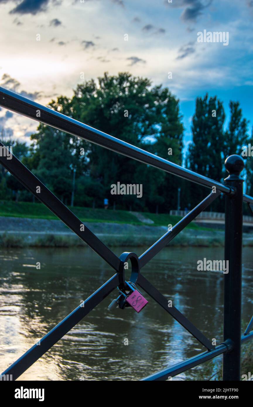Un primo piano verticale di un lucchetto rosa bloccato su un ponte Foto Stock