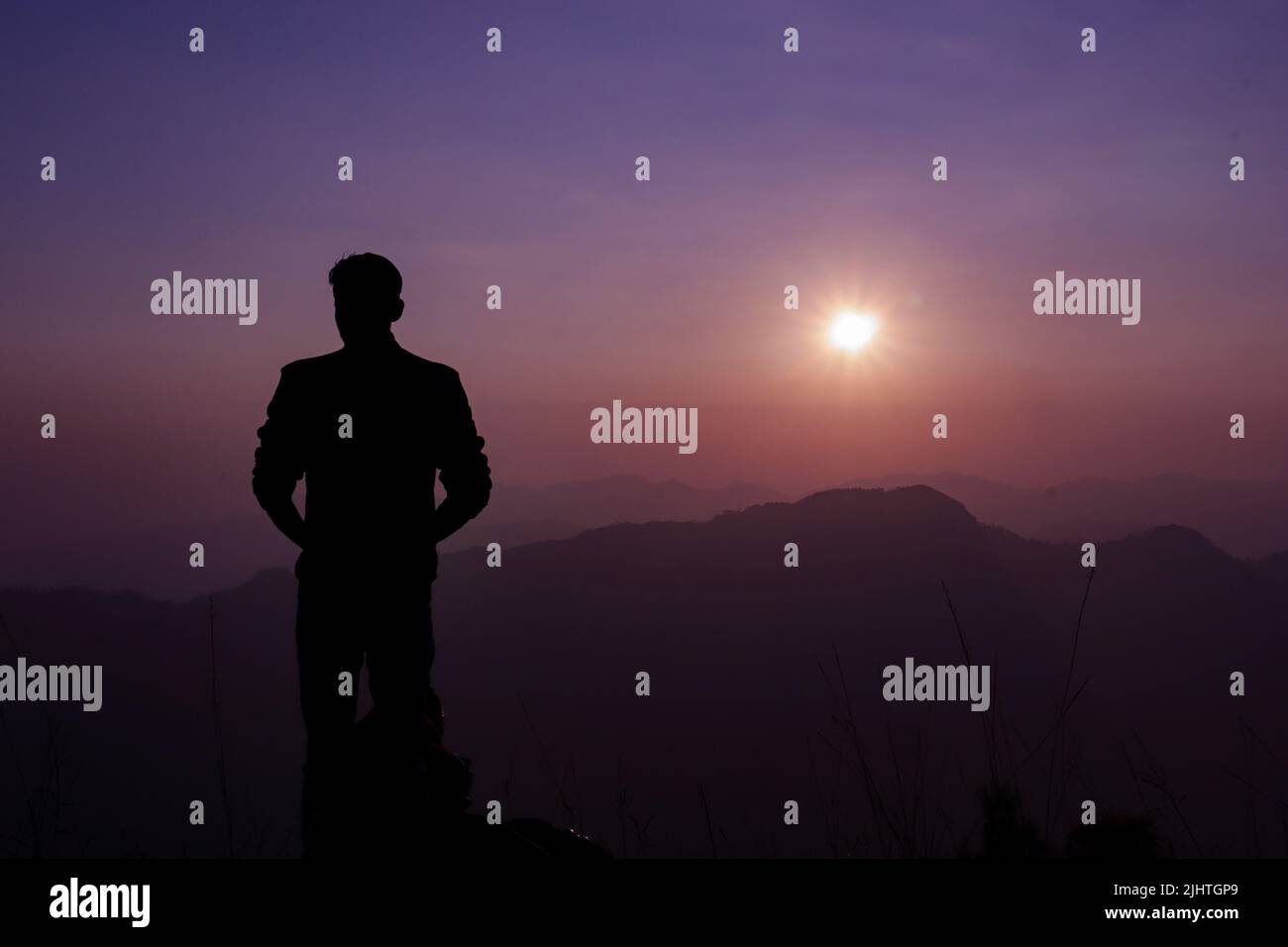 Una silhouette di un giovane maschio su sfondo viola al tramonto Foto Stock