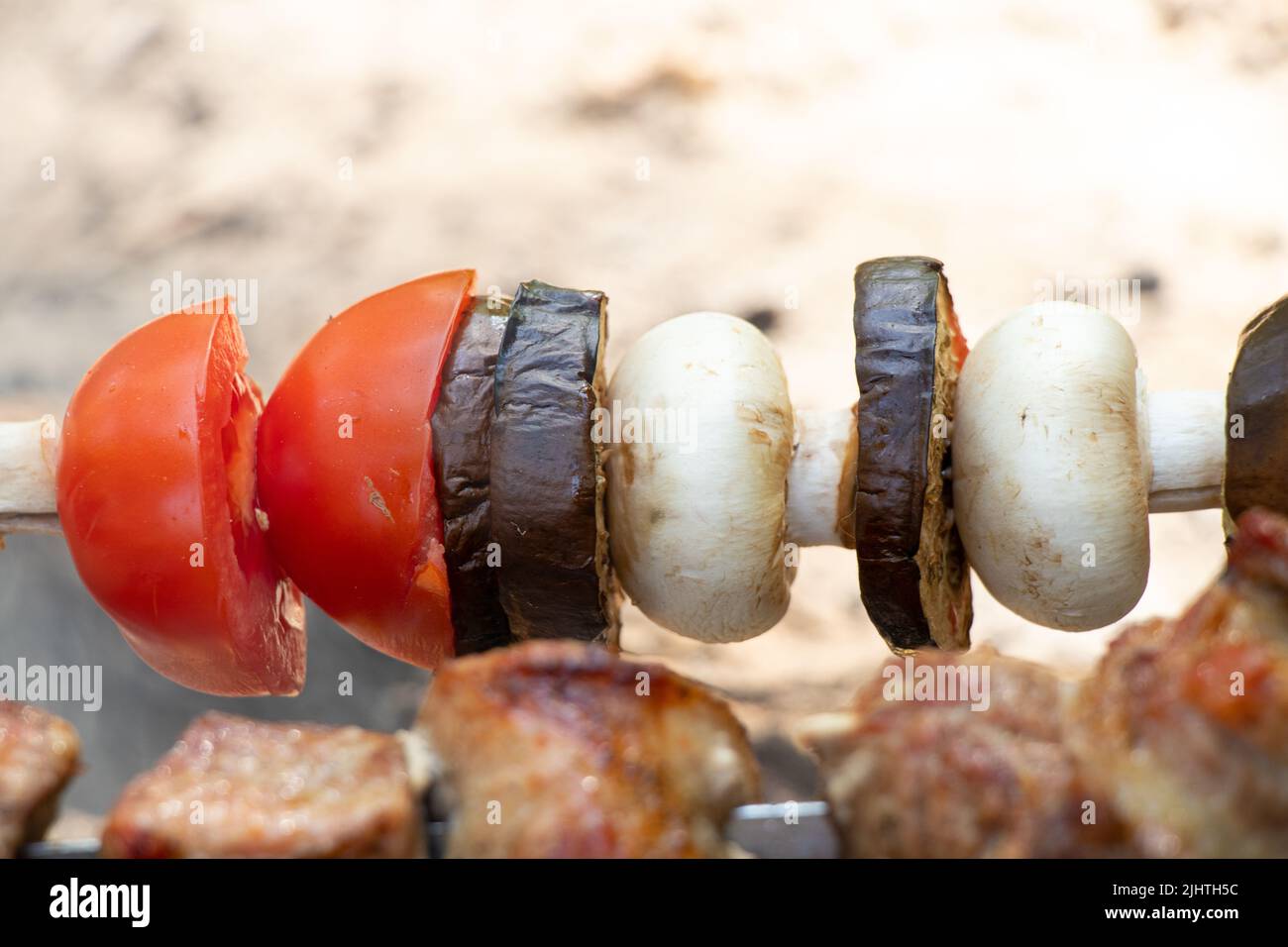 funghi fritti e pomodori con melanzane su spiedini sul fuoco nella foresta, verdure fritte sul fuoco, shashlik vegetale Foto Stock