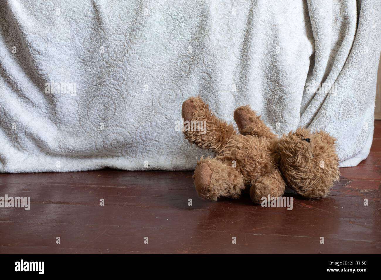 un orsacchiotto marrone si trova vicino al letto sul pavimento nella camera da letto a casa, un orsacchiotto Foto Stock