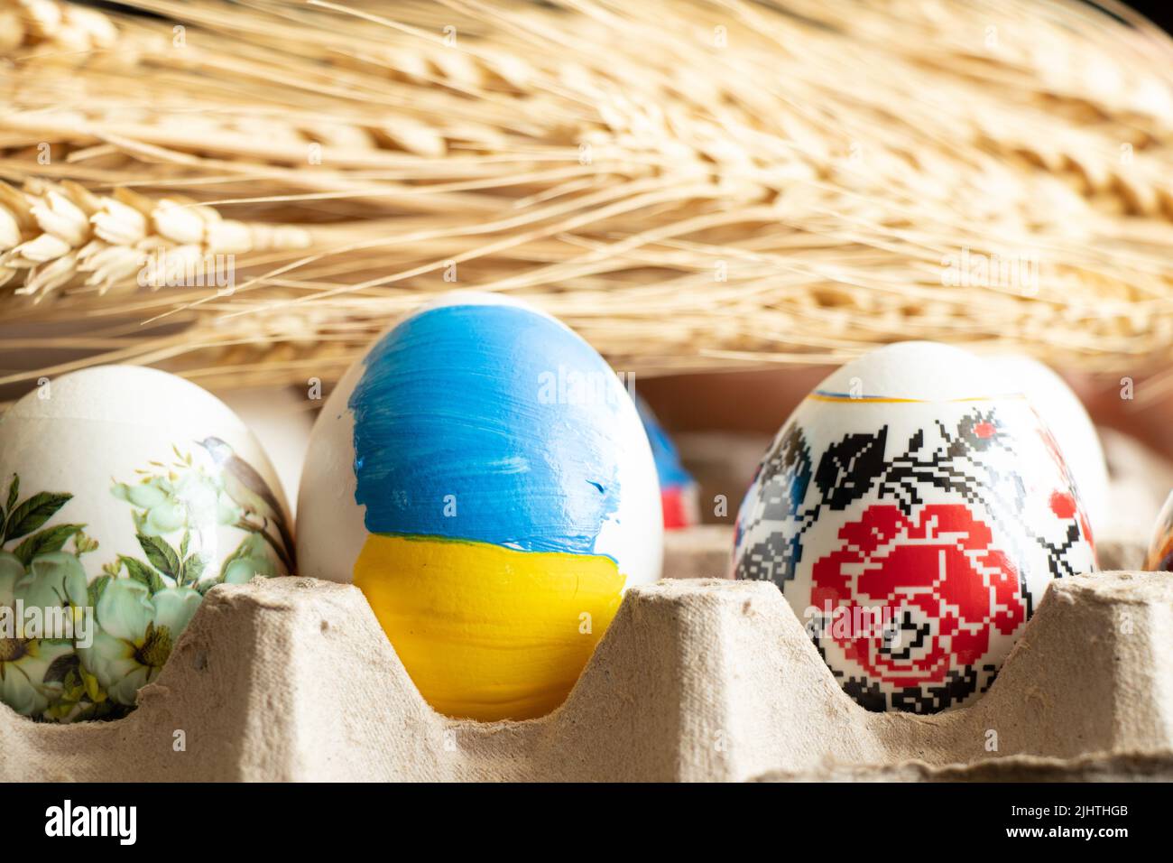 Tintura uova per pasqua in un vassoio contro lo sfondo di grano un uovo con una bandiera dipinta di guerra ucraina in ucraina per pasqua 2022.... Foto Stock