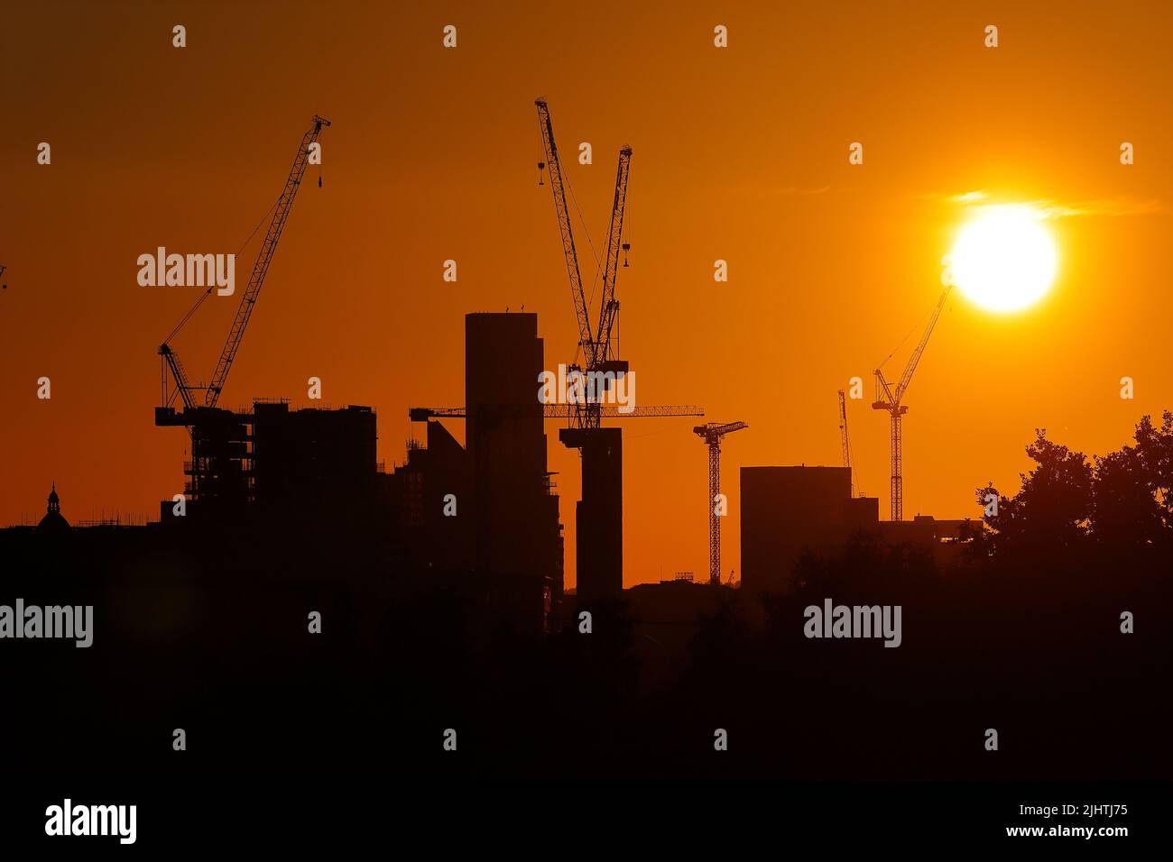 Le gru a torre si stagliano contro un'alba nel centro di Leeds, West Yorkshire, Regno Unito Foto Stock