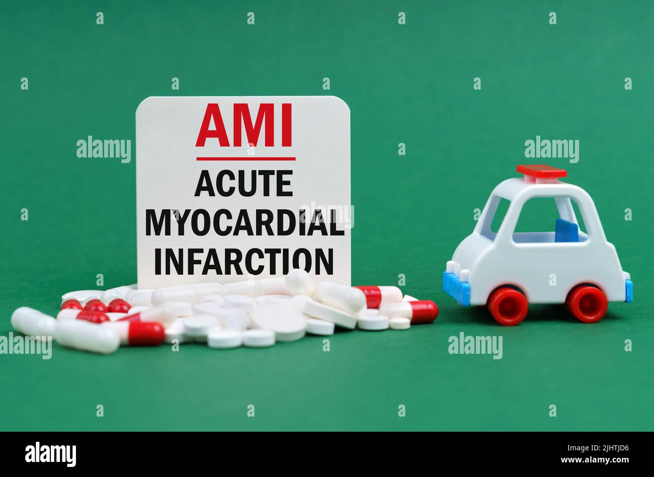 Concetto medico. Su una superficie verde, un'ambulanza, pillole e un segno bianco con l'iscrizione - infarto miocardico acuto Foto Stock