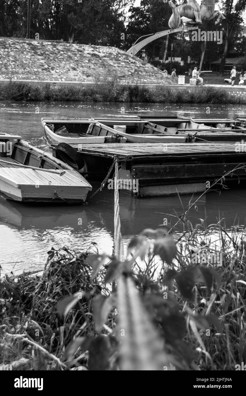 Una scala di grigi verticale di vecchie barche sul molo Foto Stock