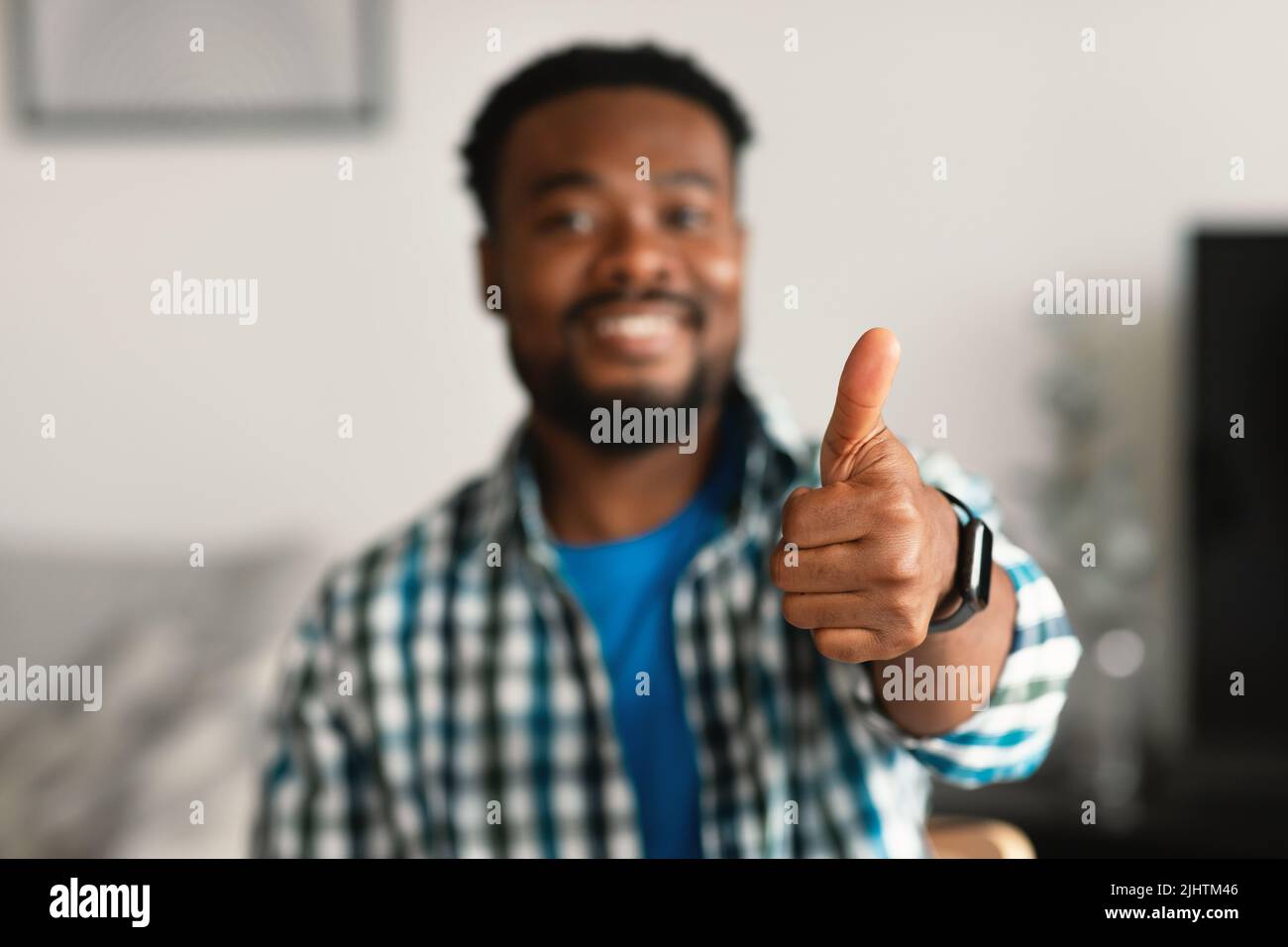 Allegro ragazzo americano africano gesturante pollice su seduta a casa Foto Stock