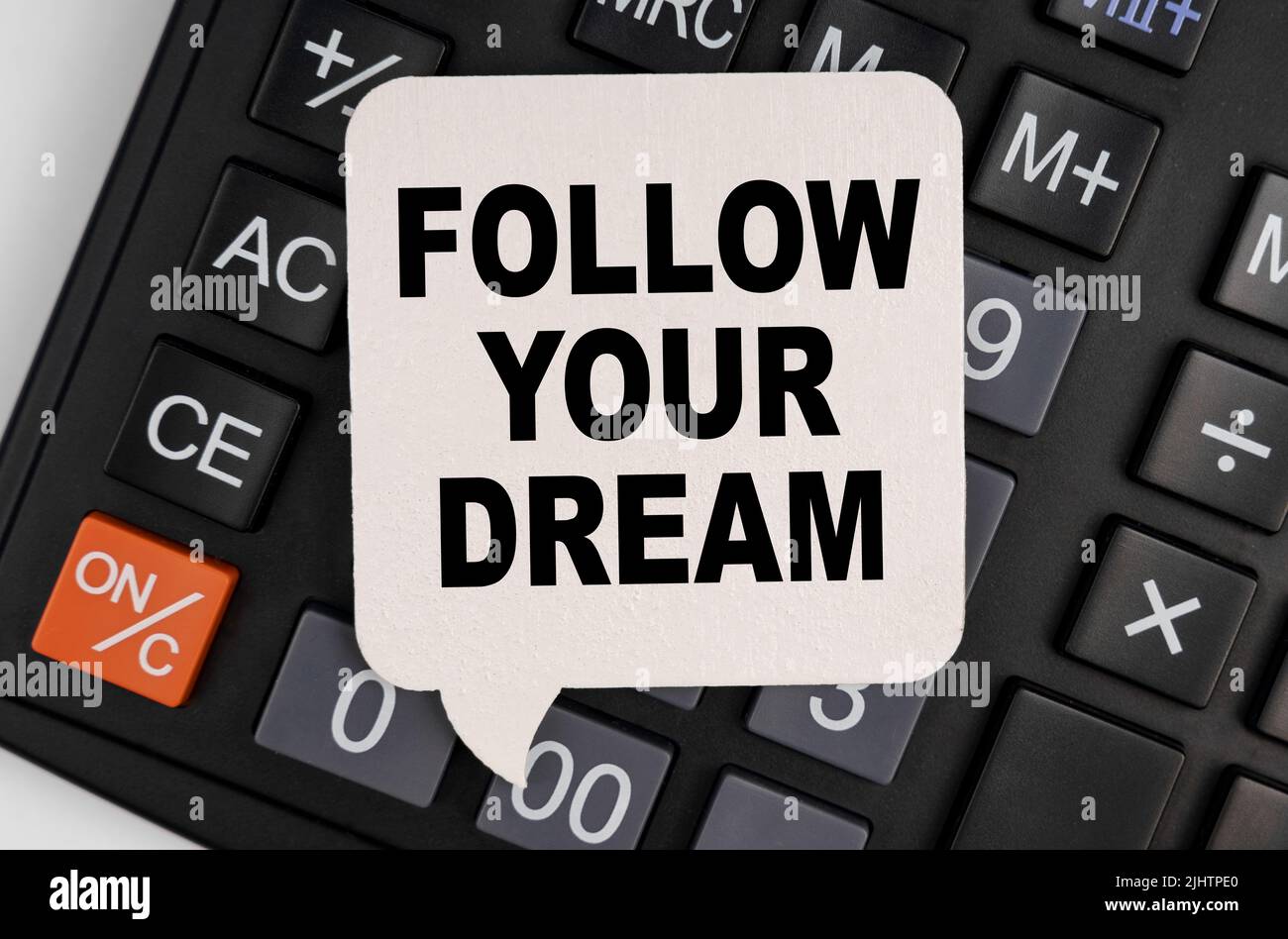 Concetto di economia e business. C'è una piastra bianca sulla calcolatrice con l'iscrizione - SEGUITE IL VOSTRO SOGNO Foto Stock
