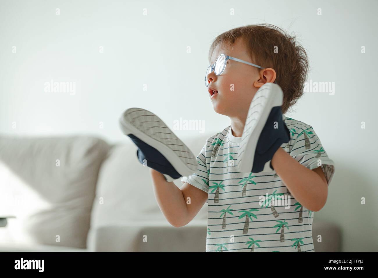 Bambino con autismo in occhiali giocare con le sue scarpe Foto Stock