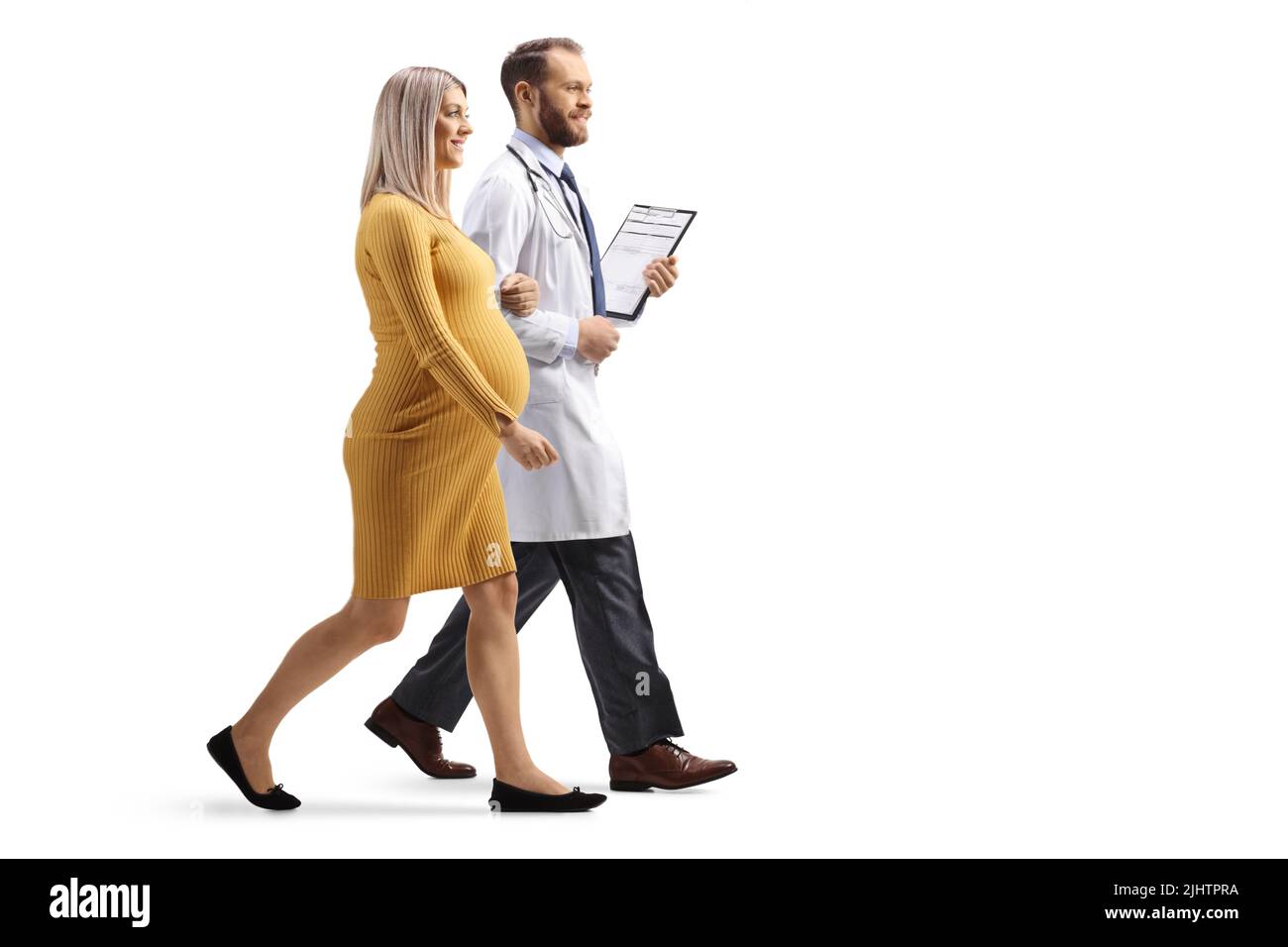 Shot di profilo a tutta lunghezza di un medico che tiene una donna incinta sotto il braccio e che cammina isolato su sfondo bianco Foto Stock