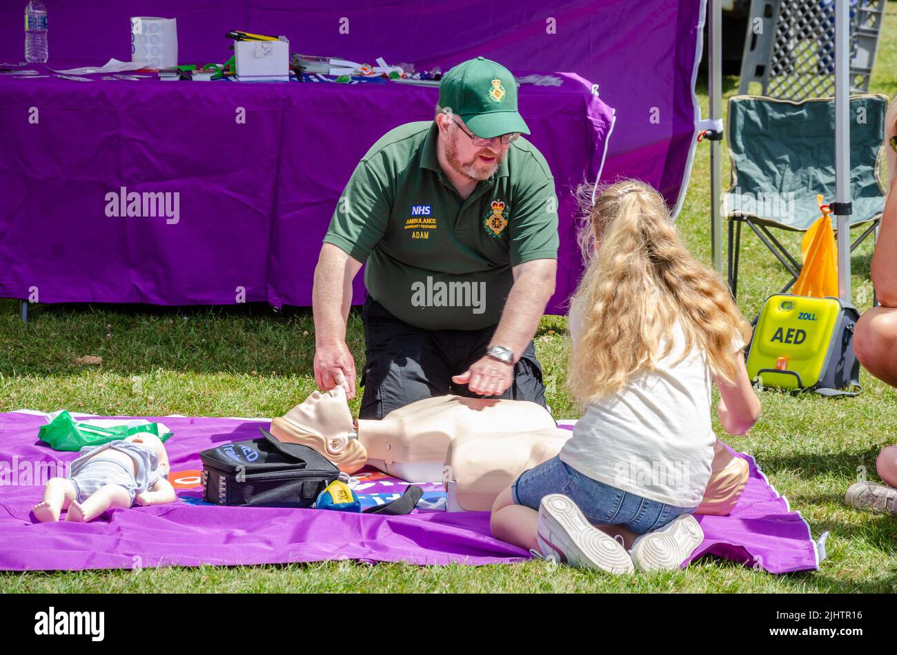 Un paramedico che insegna a una ragazza come fare CPR su un manichino al Berkshire Motor Show di Reading, Regno Unito Foto Stock