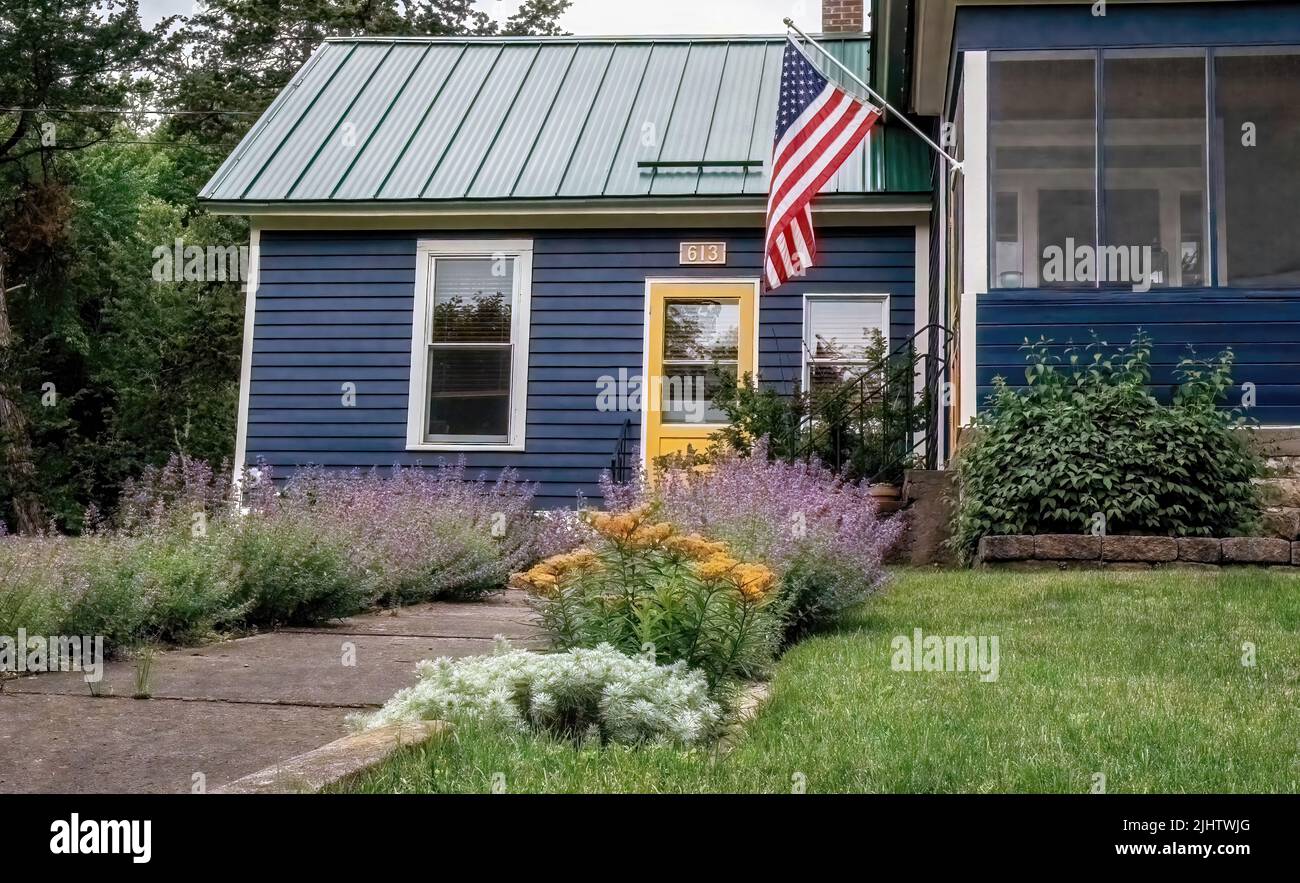 Bella catmint viola che fiancheggiano la passerella con una bandiera americana appesa fuori dal portico su una casa storica costruita nel 1861 a Taylors Falls, Minnesota Foto Stock