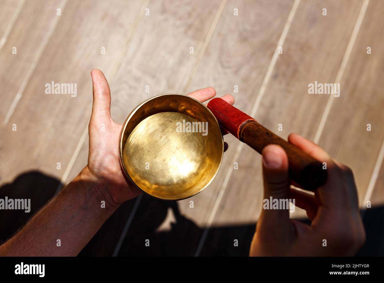 L'uomo mani usando la ciotola di canto nella terapia healing del suono all'aperto, primo piano. Foto Stock