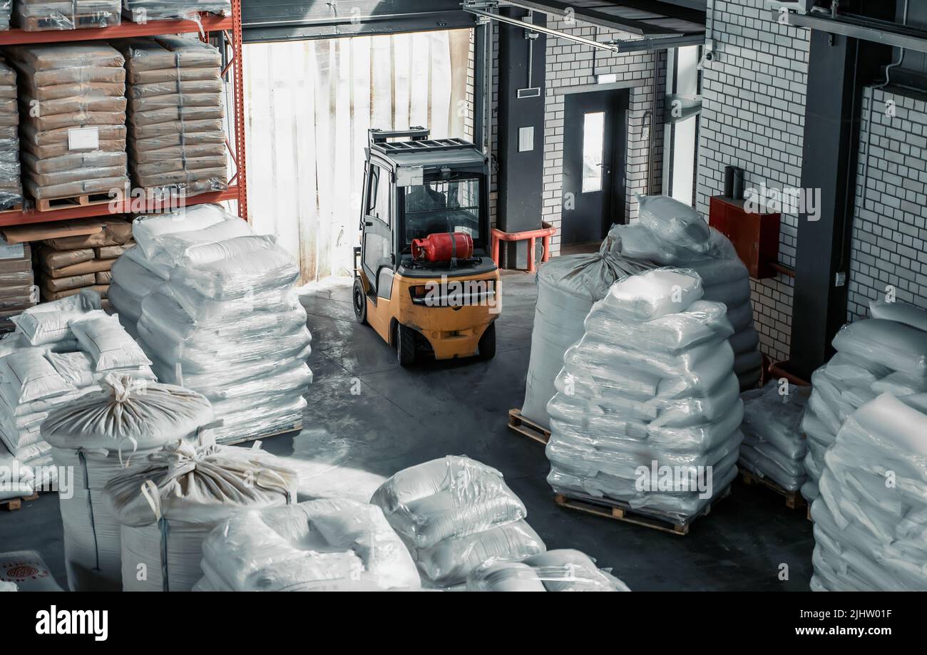 Carrello elevatore in magazzino con sacchi di grano per l'esportazione. Concetto di distribuzione e logistica. Foto Stock