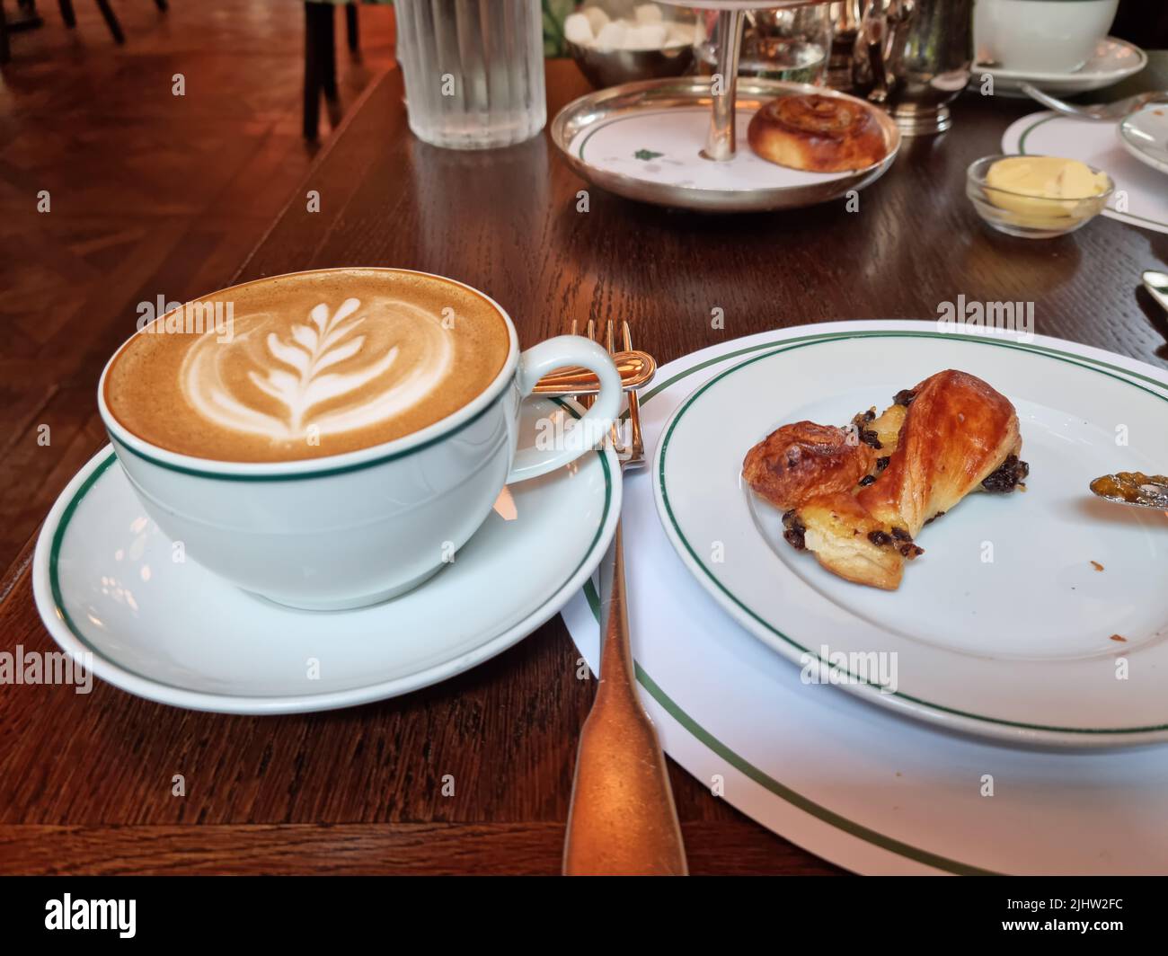 Tavolo da colazione con cappuccino e pane pain au raisin Foto Stock
