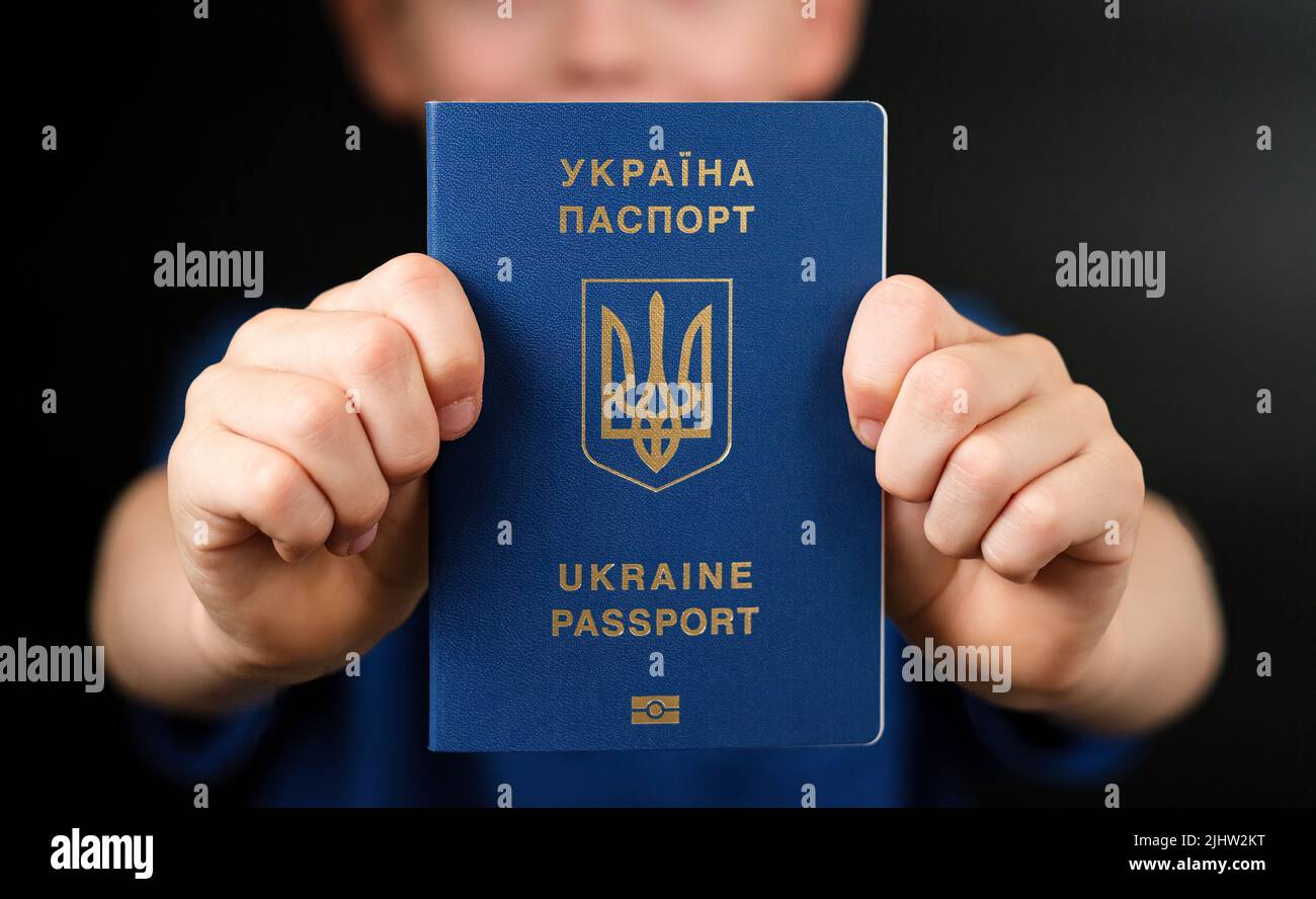 Passaporto biometrico internazionale ucraino visto nelle mani di un bambino. Concetto di viaggio e immigrazione. Foto Stock