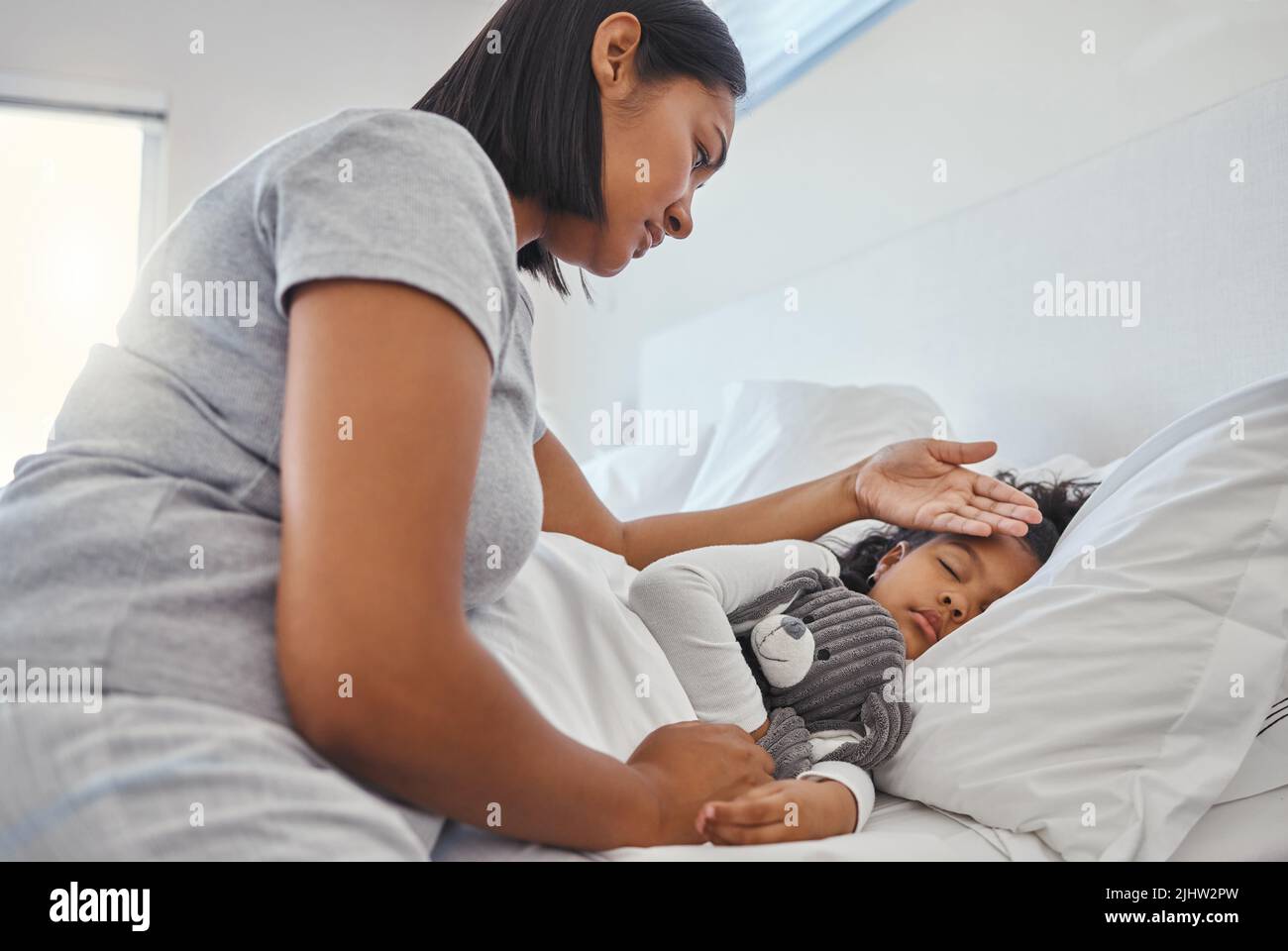 Nurse mom. Una donna che prende la sua temperatura delle figlie giovani a casa. Foto Stock