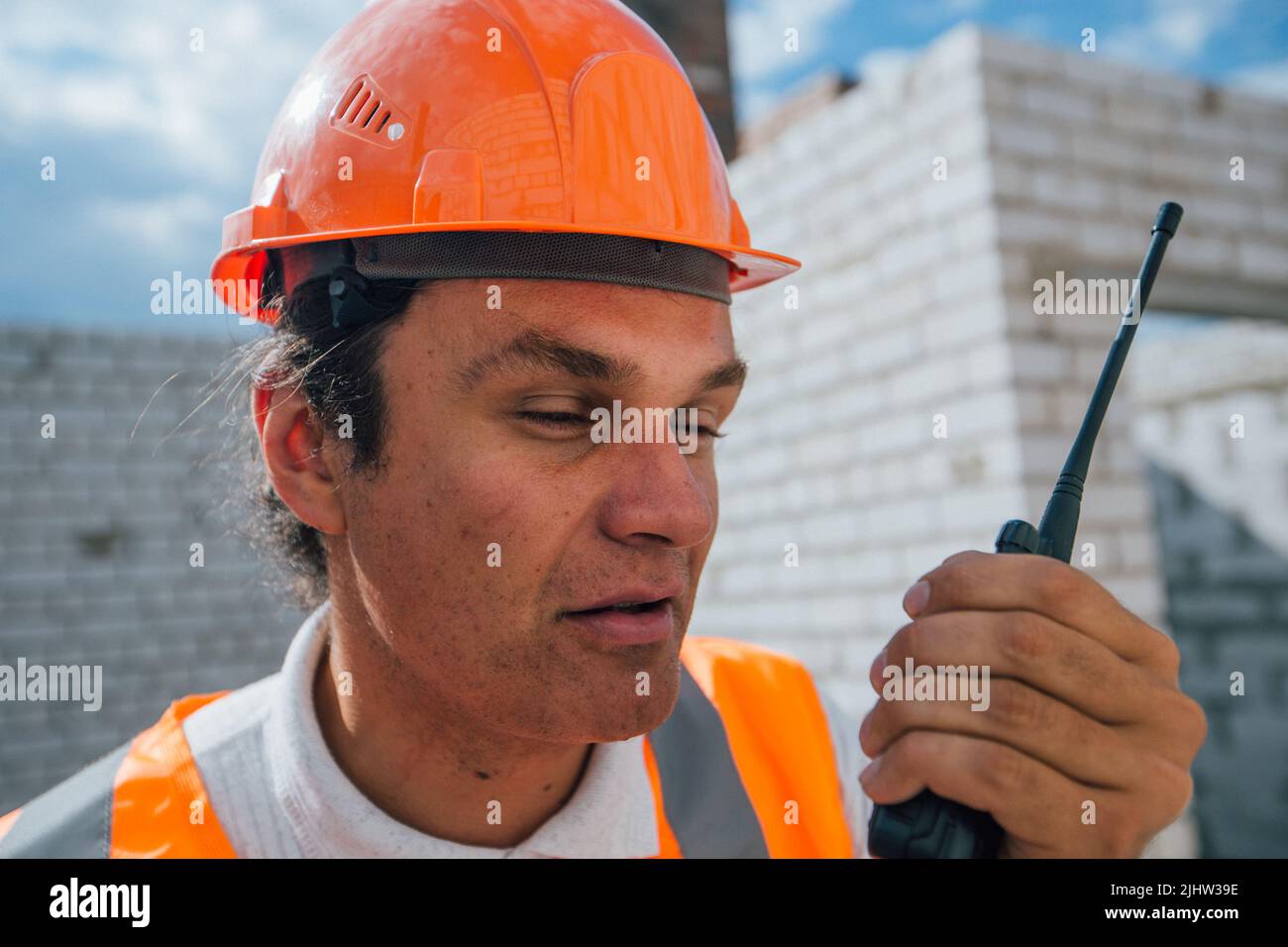 Il lavoratore di costruzione nel casco parla alla radio Foto Stock