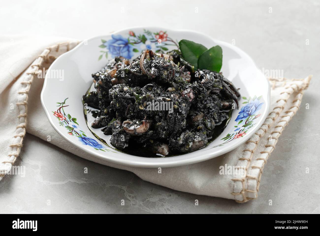 Tumis Cumi Hitam o Stir Fry Squid in Black Ink Sauce. Cucina tradizionale indonesiana a base di calamari con condimento piccante. Primo piano Foto Stock
