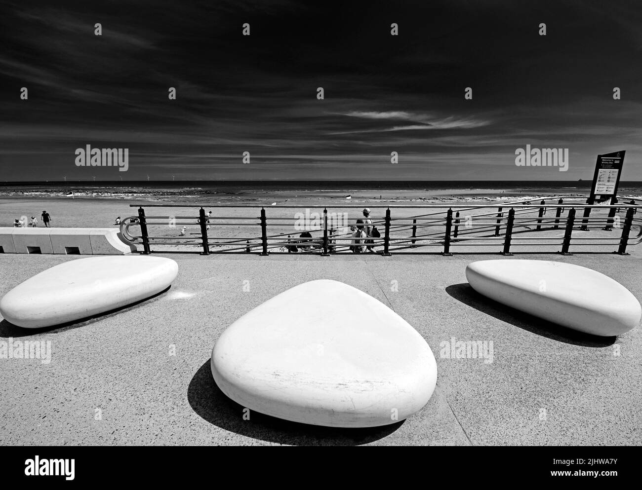 Whitley Bay Promenade in una giornata di sole sulla spiaggia con tre grandi sedili a forma di pietra il mare del Nord e un cielo blu profondo con nuvola di cirrus Foto Stock