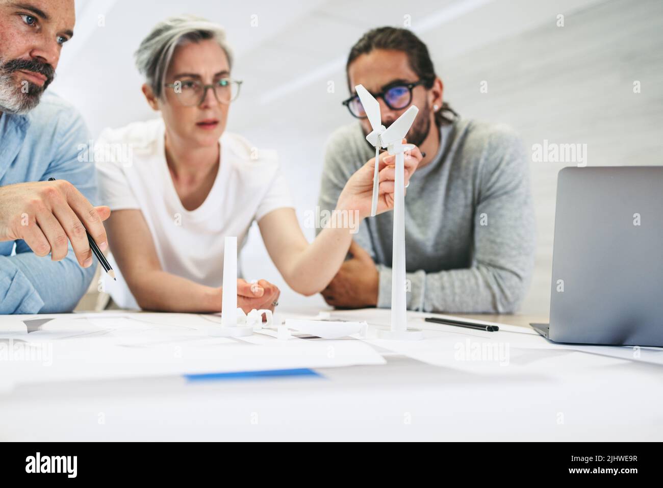 Imprenditori innovativi che lavorano con 3D modelli di turbine eoliche in un ufficio moderno. Gruppo di professionisti del design creativo che hanno una discussione mentre wor Foto Stock