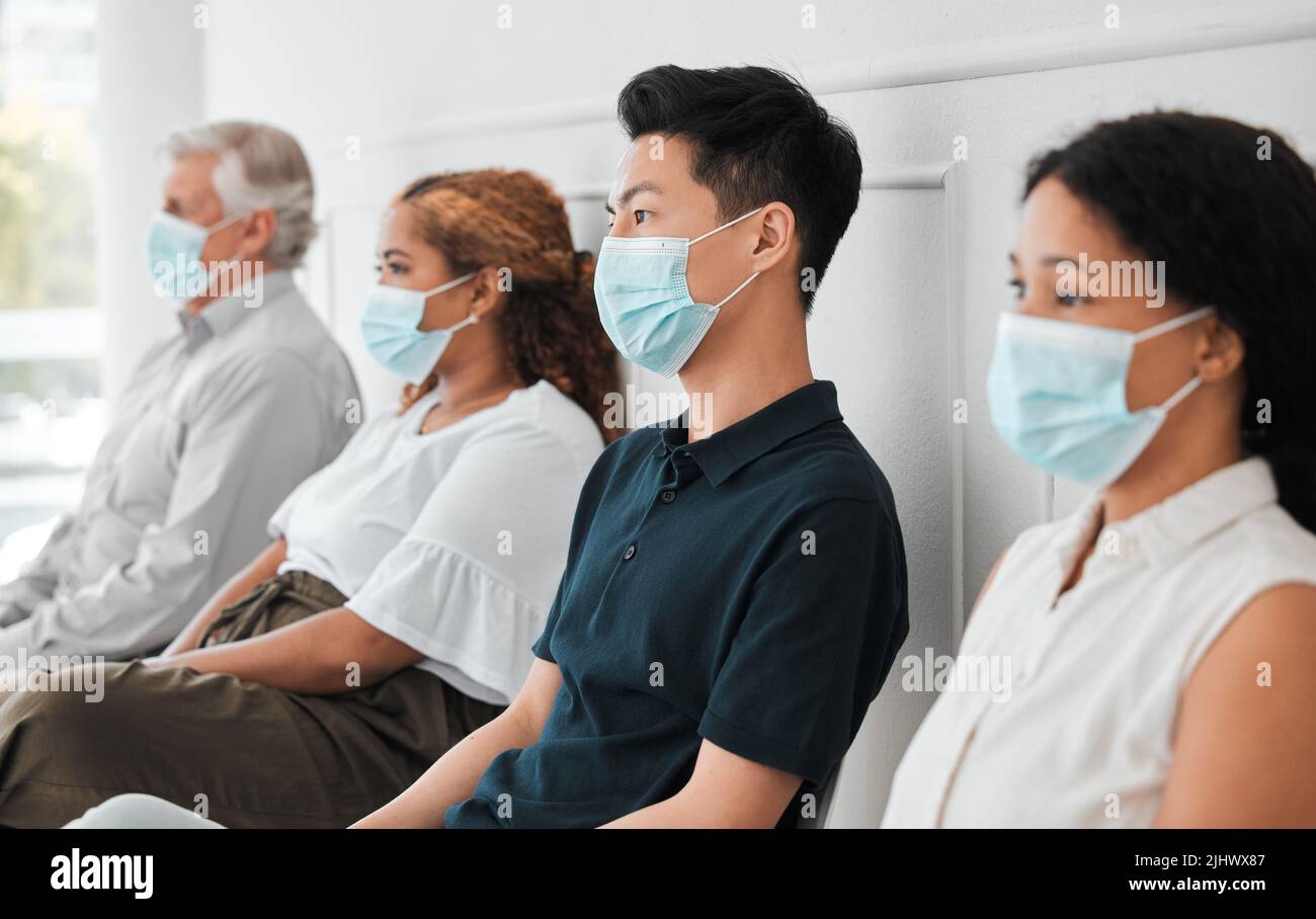 Dobbiamo fare il possibile per frenare la diffusione: Un gruppo di persone che indossano maschere per il viso mentre si siedono in fila. Foto Stock