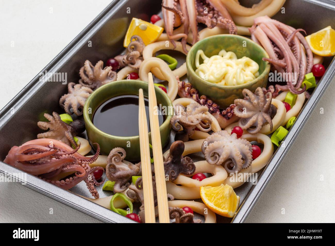 Bastoncini di bambù su una ciotola con salsa di soia tra i frutti di mare nel vassoio da forno. Vista dall'alto. Sfondo bianco Foto Stock