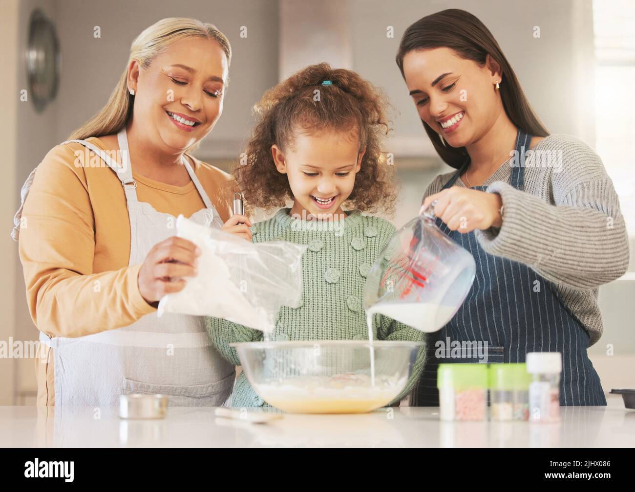 Non vogliamo che una generazione si lasci sfuggire questa deliziosa ricetta: Una bambina che cuoce con la madre e la nonna a casa. Foto Stock