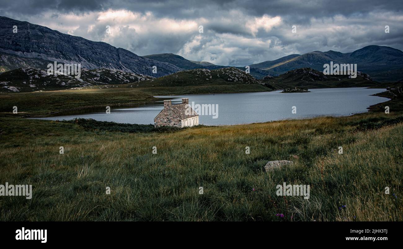 Il remoto altopiano Bothy seduta in solitudine sulle rive del Loch Stack.Wwith montagna cime di Arkle in background Foto Stock