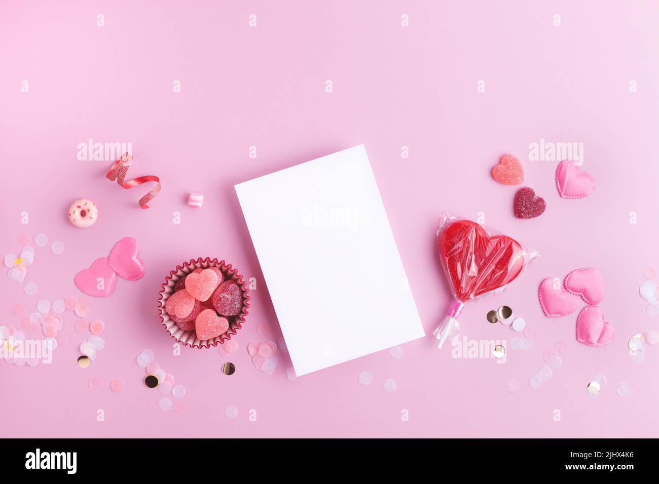 Giornata di San Valentino bella festa rosa sfondo con cuori, confetti e carta bianca per il tuo disegno. Disposizione piatta con spazio vuoto. Foto Stock