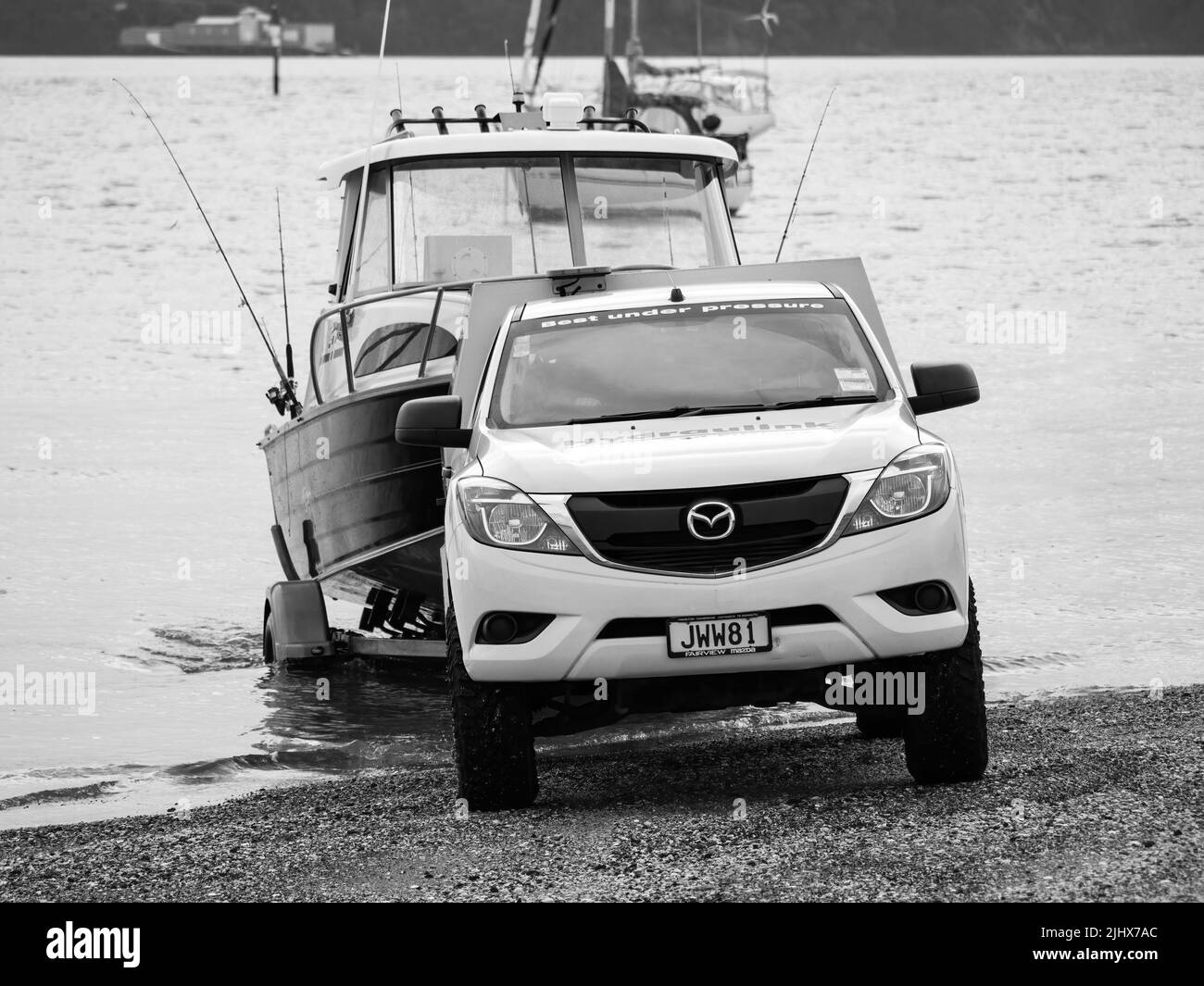 Mazda BT-50 Generation II (2011-2015) bianco, autocarro che tira fuori dall'acqua la traina di un rimorchio di Fyran. Auckland, Nuova Zelanda - 8 giugno 2022 Foto Stock