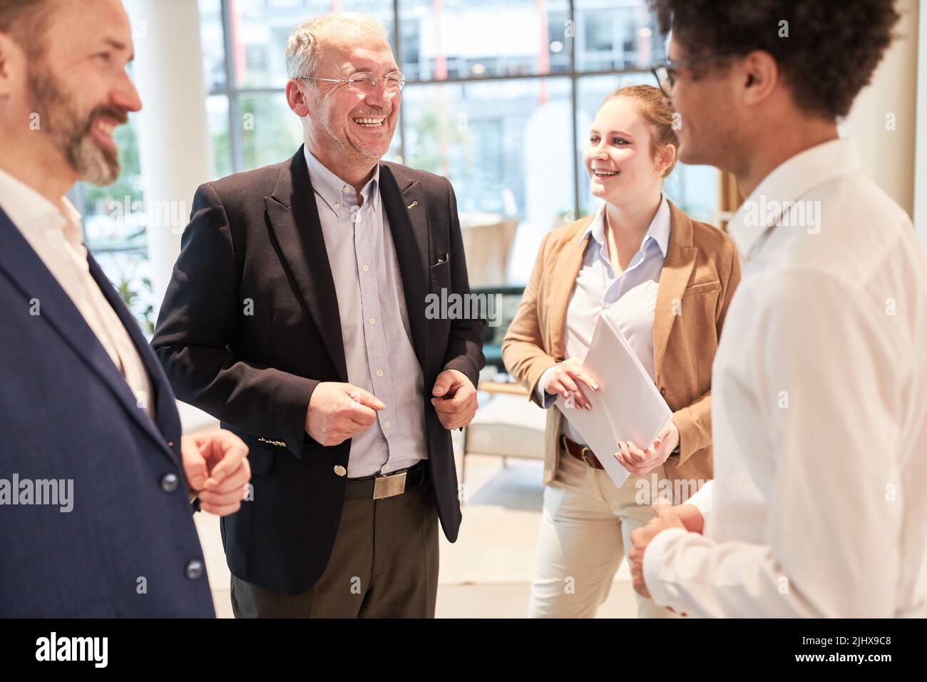 Gruppo di uomini d'affari che ridono insieme a una barzelletta in una pausa dopo la riunione Foto Stock