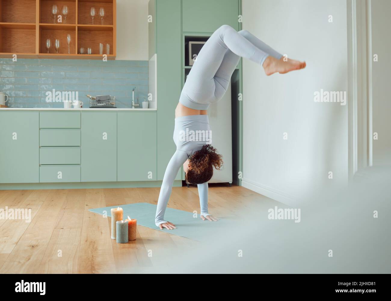 Bella giovane donna da corsa mista che pratica yoga a casa. La femmina ispanica che fa pilates l'esercitazione come parte del suo workout. Allenarsi per tenere la sua mente Foto Stock