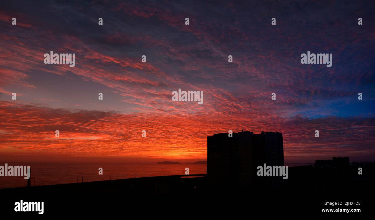 Cielo crepuscolo dopo il tramonto, nuvole in rosso, arancione, blu, viola, viola, colori crimson. Silhouette di costruzione. Sfondo colorato skyline. Foto Stock