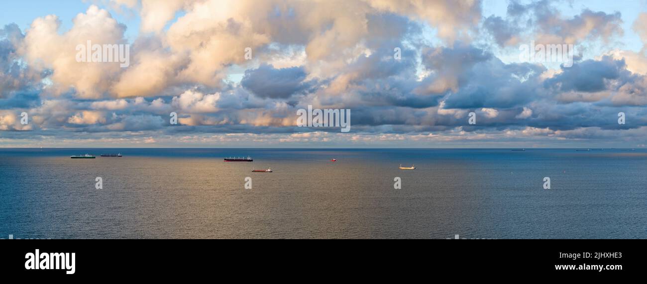 Moody cielo su navi container nuoto sul golfo del mare, paesaggio aereo al crepuscolo Foto Stock