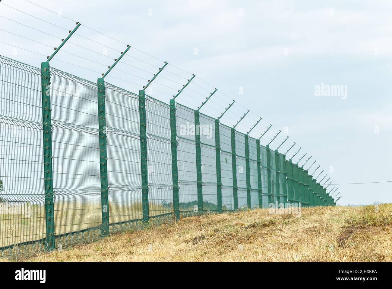 Recinzione di sicurezza di nuova costruzione con fili elettrificati lungo il confine della proprietà all'aperto giorno estati. Foto Stock