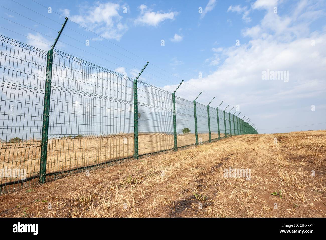 Recinzione di sicurezza di nuova costruzione con fili elettrificati lungo il confine della proprietà all'aperto giorno estati. Foto Stock