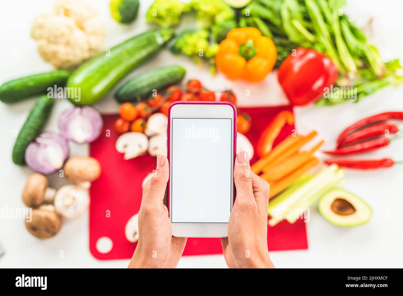 Cercate una ricetta su internet con il telefono cellulare a base di ingredienti vegetali Foto Stock