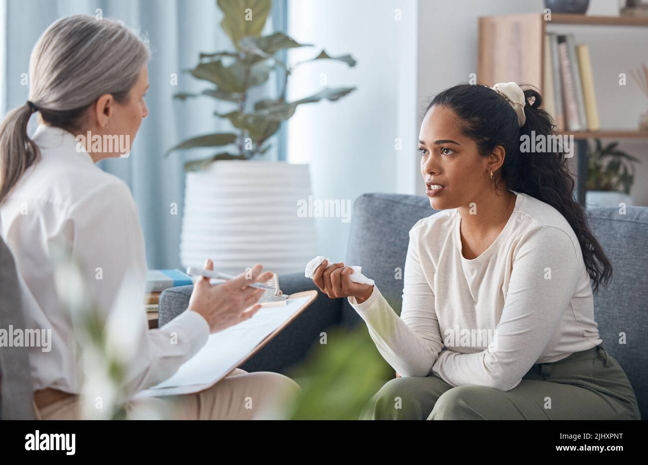 Come faccio a impedire che accada: Una giovane donna attraente seduta e che parla con la sua psicologa durante una consultazione. Foto Stock