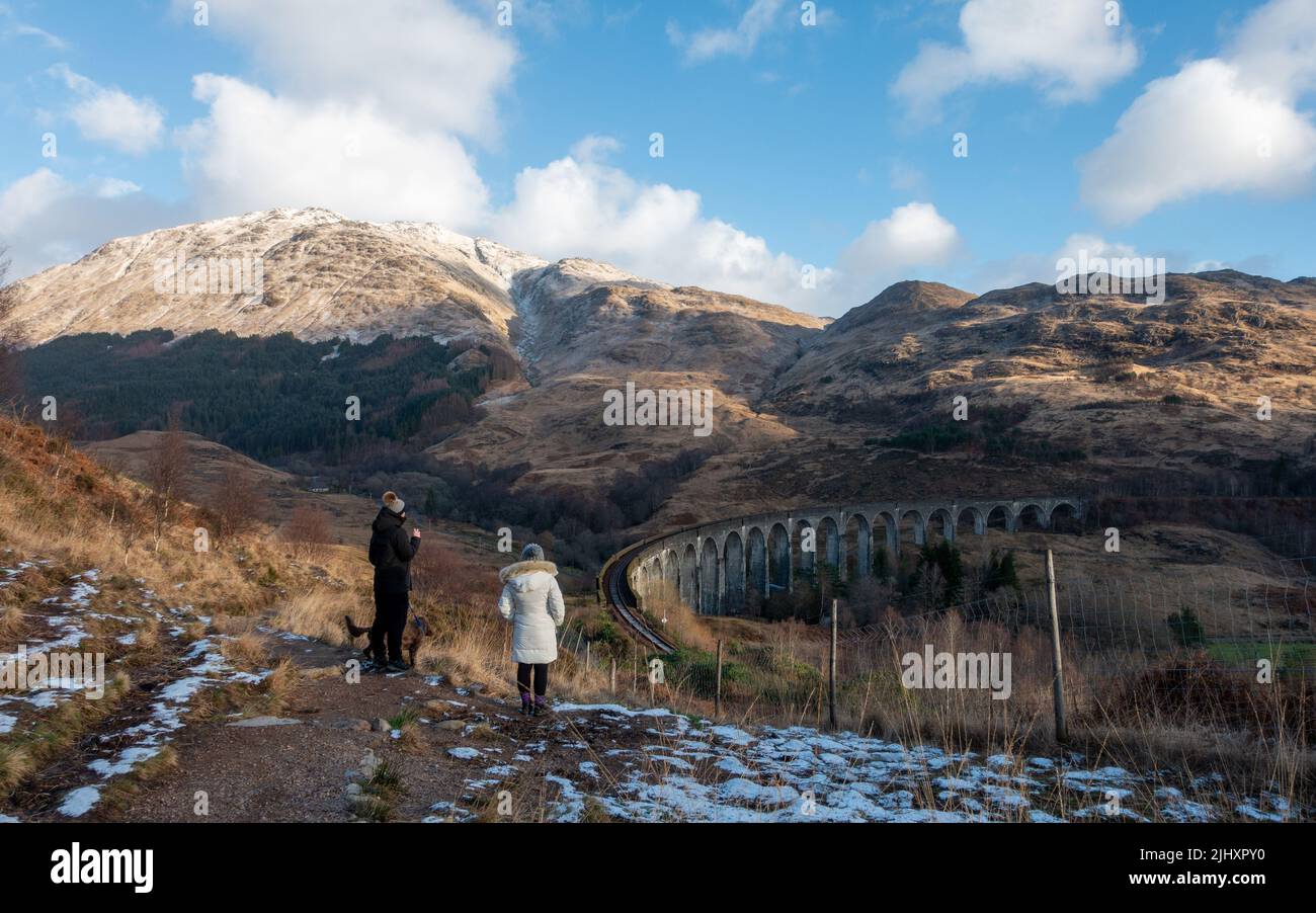 Paesaggio scozzese e passeggiate invernali: Persone che godono la vista della neve sulle piste del viadotto Glenfinnan, Scozia Foto Stock