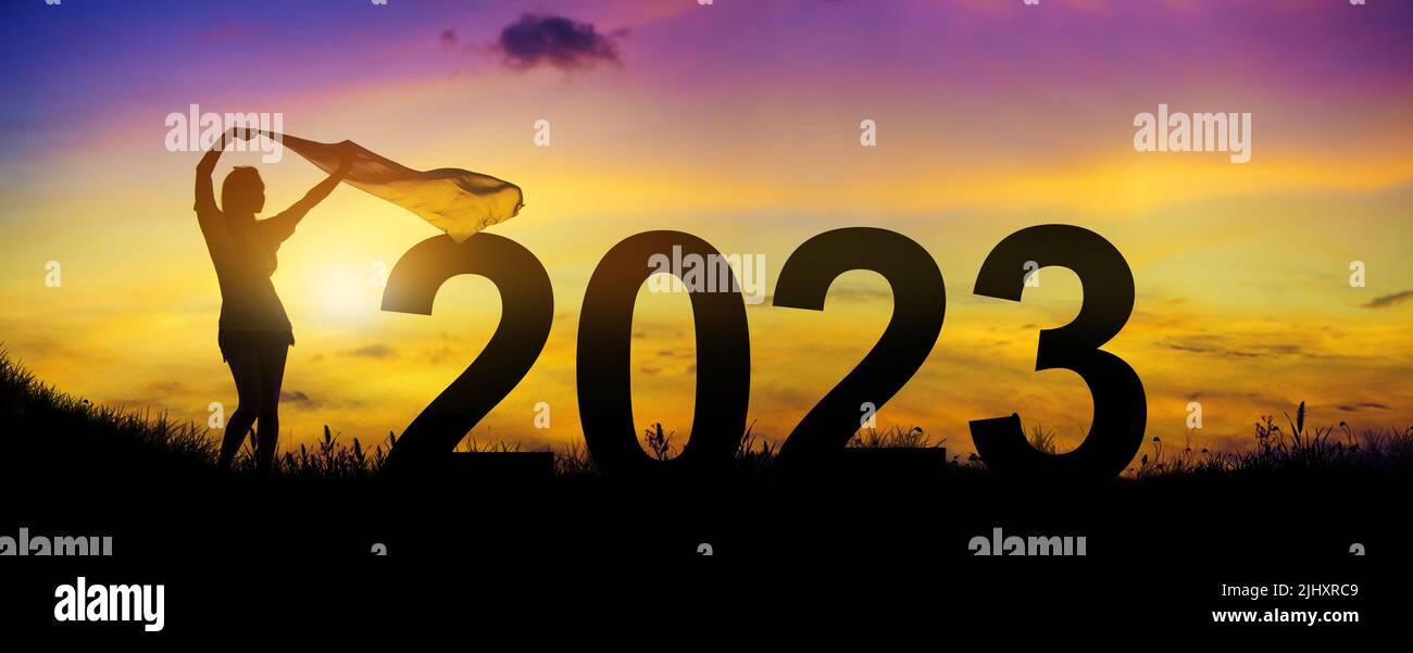 Benvenuti buon Natale e felice anno nuovo nel 2023. Silhouette che si gode le donne che si sfoggiano un tessuto sottile sulla collina mentre festeggia 2023 anni nella t Foto Stock