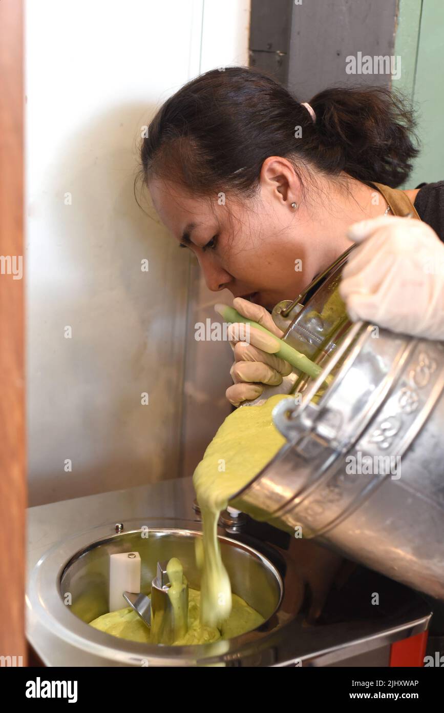 Donna vietnamita che sposta il gelato fatto in casa da secchio in mixer Foto Stock