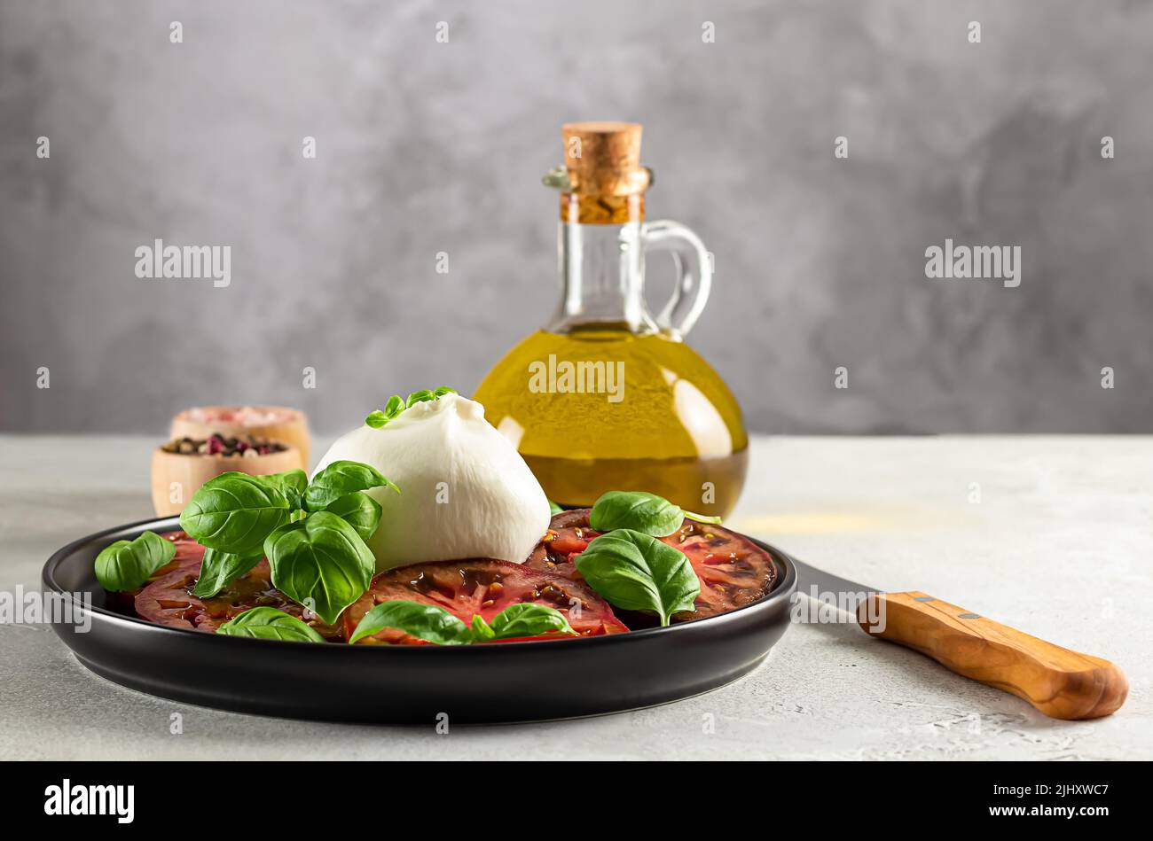 Burrata servito con pomodori freschi, oli d'oliva e foglie di basilico. Foto Stock
