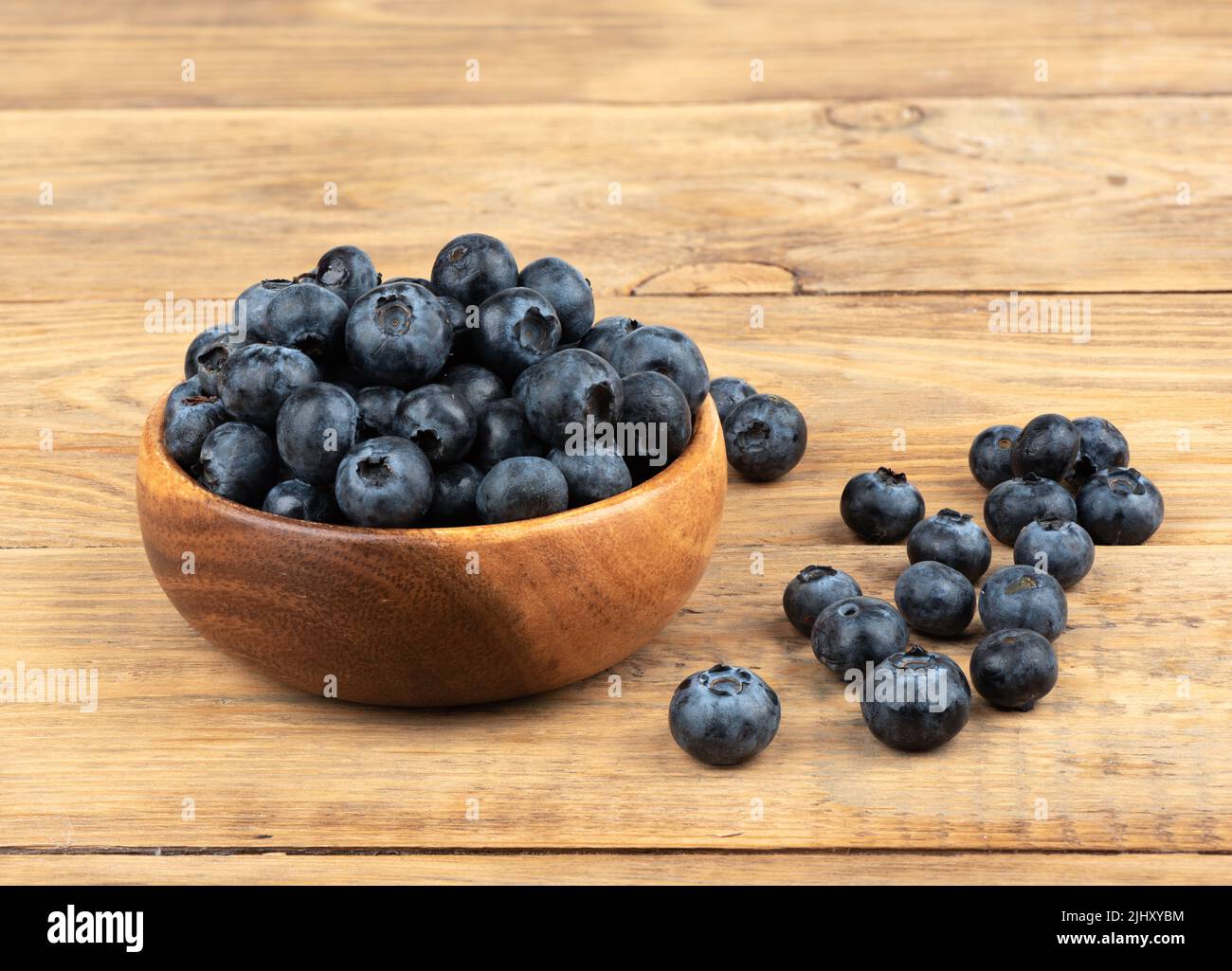 Mirtillo o mirtillo o whortleberry blu o mirtillo in ciotola di legno su sfondo di legno. Mirtillo comune lat Vaccinium uliginosum. Spazio di copia. Foto Stock